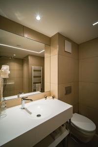 a bathroom with a sink and a toilet and a mirror at Eleven Business & Sport Hotel in Jászárokszállás