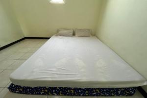 Cama blanca grande en una esquina de habitación en OYO Life 92982 Kost Berkah Ibu, en Lawang