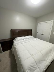 - une chambre avec un grand lit blanc et une tête de lit en bois dans l'établissement Dhimanz Residence, à Surrey