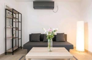 a living room with a couch and a vase of flowers on a table at "One minute from sea" from Shneider Apartments in Haifa