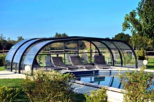a swimming pool with a glassconservatory in a garden at La Grange 