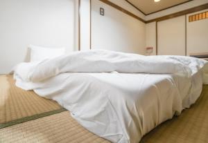 a bed with white sheets on the floor in a room at HANASTAY花渓居 野田Noda in Osaka