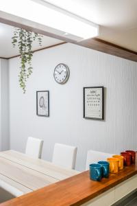 a dining room table with chairs and a clock on the wall at HANASTAY花渓居 野田Noda in Osaka