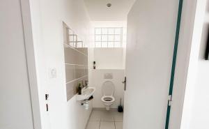 a white bathroom with a toilet and a sink at Ty Maud' calme et spacieux in Concarneau