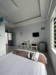 Dormitorio blanco con cama y mesa en Tony's House Hotel Mũi Né, en Ấp Thiện Phước