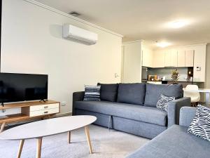 Una sala de estar con un sofá azul y un televisor. en ReadySet Apartments at Sentinel, en Melbourne