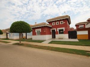 a red and white house with a tree in front of it at Villa Amyali by Rentalole Mar Menor Golf Resort in Torre-Pacheco