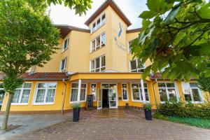 un edificio amarillo con la parte delantera en Einklang - Dein Hotel am Südhorn, en Wendisch Rietz