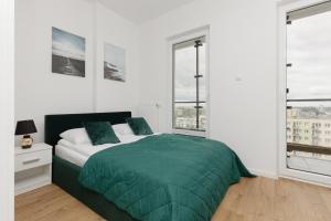 ワルシャワにあるBusiness Apartments Kasprzaka by Noclegi Rentersのベッドルーム1室(緑のベッド1台、窓2つ付)