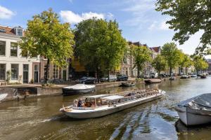 a boat traveling down a river in a city at Breathe Hotel Leiden in Leiden