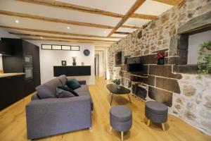ein Wohnzimmer mit einer Steinmauer, einem Sofa und einem Stuhl in der Unterkunft Le Coeur de Ville splendide T2 plein centre in Annecy