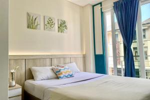 een slaapkamer met een bed en een raam met blauwe gordijnen bij Behomy 3C Residence near ICE BSD in Tangerang