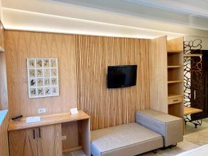 a room with a tv on a wooden wall with a shelf at Dimora Storica Torre Del Parco 1419 in Lecce