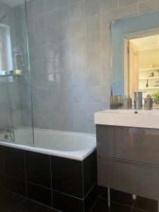 a bathroom with a tub and a sink and a mirror at LondonHomeGardens in London