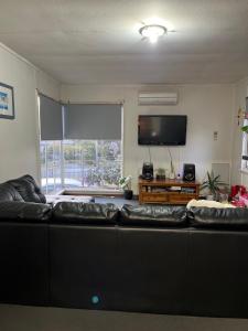 sala de estar con sofá negro y TV en Jennifer, en Warrane