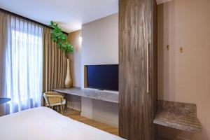 a bedroom with a bed and a tv and a desk at Breathe Boutique Hotel in Leiden