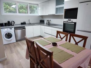 uma cozinha com uma mesa e uma cozinha com armários brancos em Milly's House em Esposende