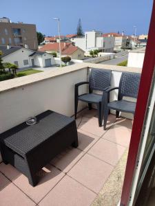 een patio met 3 stoelen en een tafel op een balkon bij Milly's House in Esposende