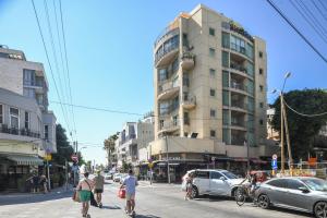 Leute überqueren eine belebte Straße vor einem hohen Gebäude in der Unterkunft Elegant Sea-View Apartment with Mamad in the Heart of Tel Aviv by Sea N' Rent in Tel Aviv
