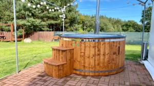 a wooden hot tub with two benches in a backyard at Leśna Oaza in Sasino