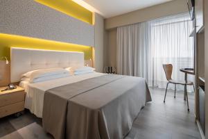 Hotel Rosanna 3 Stelle Superior في ليدو دي يسولو: غرفة الفندق بسرير كبير ومكتب
