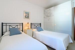 2 bedden in een slaapkamer met witte lakens en blauwe kussens bij Casa Folias in Puerto del Carmen