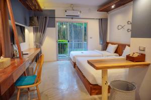 a bedroom with a bed and a desk and a table at Dugong Village-Green Hotel in Pak Meng