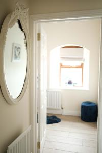 um corredor com um espelho e um banco azul em Drumnavaddy Cottage em Dromore