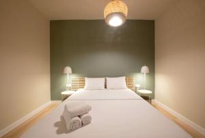 a bedroom with a white bed with two towels on it at Mandarin apartments by halu! in Thessaloniki