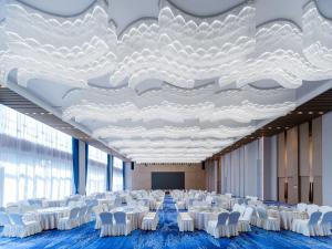 Una sala de conferencias con sillas blancas y un techo grande. en Holiday Inn Express Zhoukou Dancheng by IHG, en Zhoukou