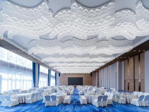 sala konferencyjna z białymi krzesłami i dużym sufitem w obiekcie Holiday Inn Express Zhoukou Dancheng, an IHG Hotel w mieście Zhoukou