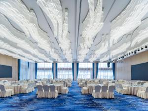 um salão de banquetes com mesas e cadeiras brancas em Holiday Inn Express Zhoukou Dancheng, an IHG Hotel em Zhoukou