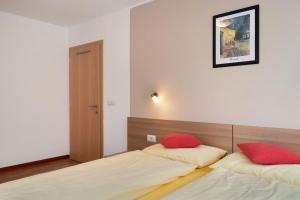 - une chambre avec 2 lits et des oreillers rouges dans l'établissement Hilber App Furchetta Small, à Villnoss