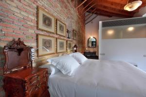プリエゴ・デ・コルドバにあるホテル パトリア チカの白いベッドとレンガの壁が備わるベッドルーム1室が備わります。