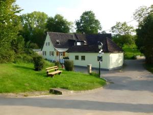 Uma casa branca com um banco à frente. em Haus Elfriede em Müllheim