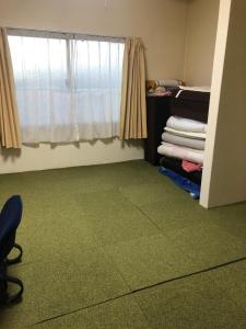 een kamer met een groen tapijt en een raam bij Guest House Kizuna in Oshamambe