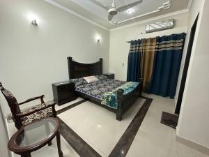 1 dormitorio con 1 cama y 1 silla en Bahria Town - 10 Marla 2 Bed rooms Portion for families only en Lahore