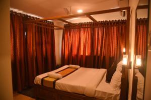 a bedroom with a canopy bed with red curtains at Morjim Stay Villa in Old Goa
