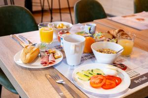 - une table avec des assiettes de produits pour le petit-déjeuner et du jus d'orange dans l'établissement KYRIAD CREIL - Chantilly Nord, à Creil