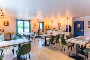un restaurant avec des tables en bois et des chaises vertes dans l'établissement KYRIAD CREIL - Chantilly Nord, à Creil