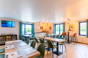 a restaurant with tables and chairs and a kitchen at KYRIAD CREIL - Chantilly Nord in Creil