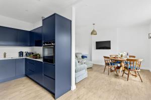 cocina con armarios azules y mesa en Landau Apartment, Stokenham en Stokenham