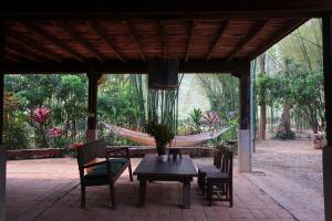 a hammock and a table with chairs and a hammock at Traditional Lanna house near hot spring in Chiang Dao