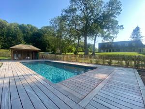 una piscina en una terraza de madera con cenador en Gîte des Etangs, en Glanville