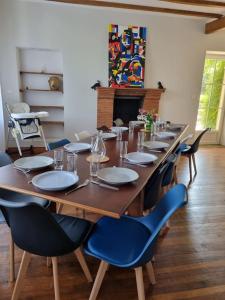 una larga mesa de madera con sillas y platos. en les glycines en Saint-Marien