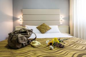 una camera d'albergo con un letto, una borsa e fiori di Hotel Gran Sasso & SPA a Teramo