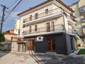 a white and black building with a balcony at Hotel Bujtina 31 in Korçë