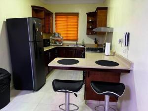 eine Küche mit einem schwarzen Kühlschrank und 2 Barhockern in der Unterkunft Apartamento entero Tu Nido De Amor 2 Santo Domingo oeste in Santo Domingo