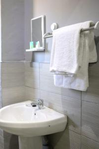 uma casa de banho branca com um lavatório e um espelho em De Ellas Boutique Lodge em Polokwane