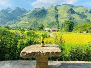 a stone table in front of a field and mountains at Du Gia Field View Homestay in Làng Cac